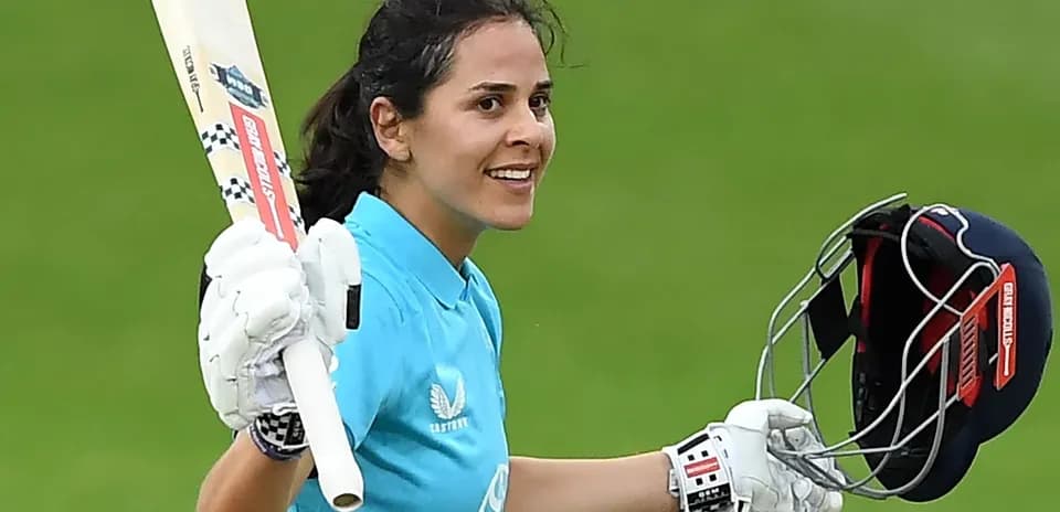 Female cricketer celebrating with bat and helmet