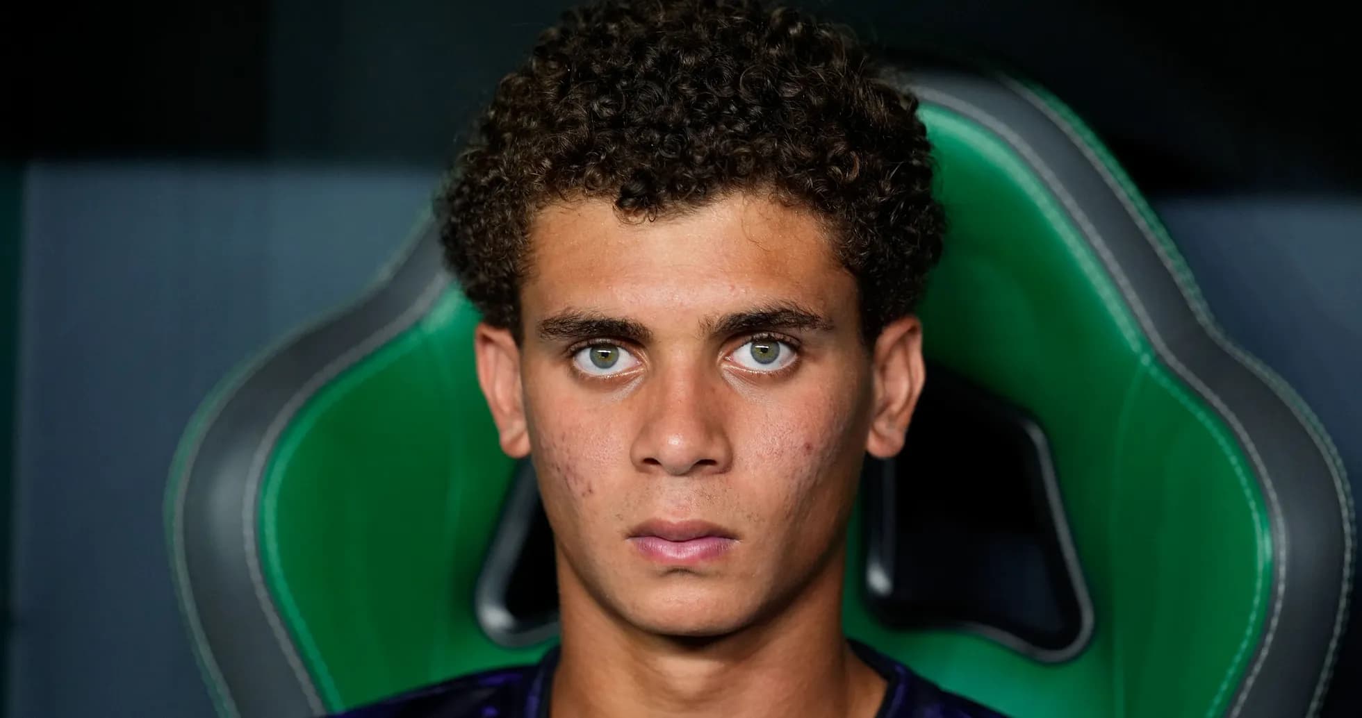 Young player sitting on bench with serious expression