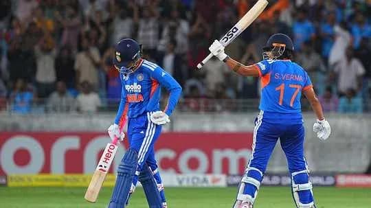 Two cricket players on the field celebrating a run