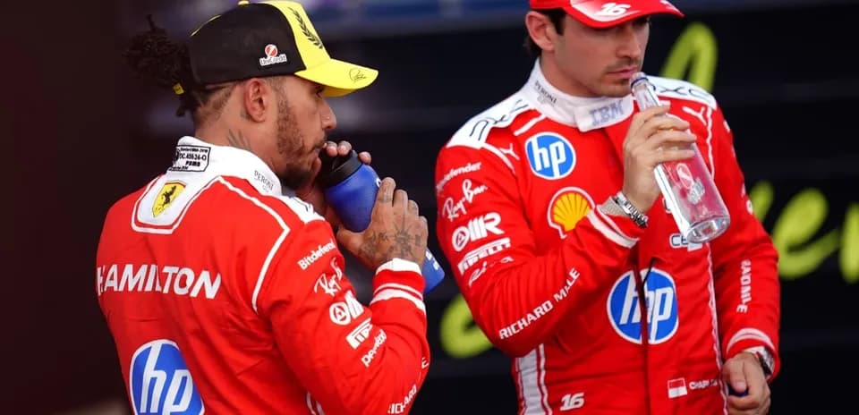 Two Formula 1 drivers hydrating in team uniforms