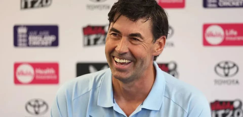 Cricket coach smiling during press conference