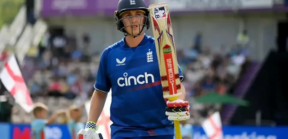 Cricketer walking off field with bat in hand