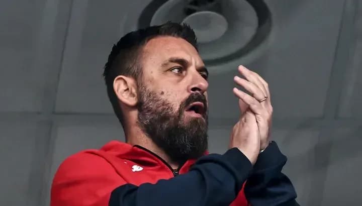 Man in red jacket applauding in a stadium