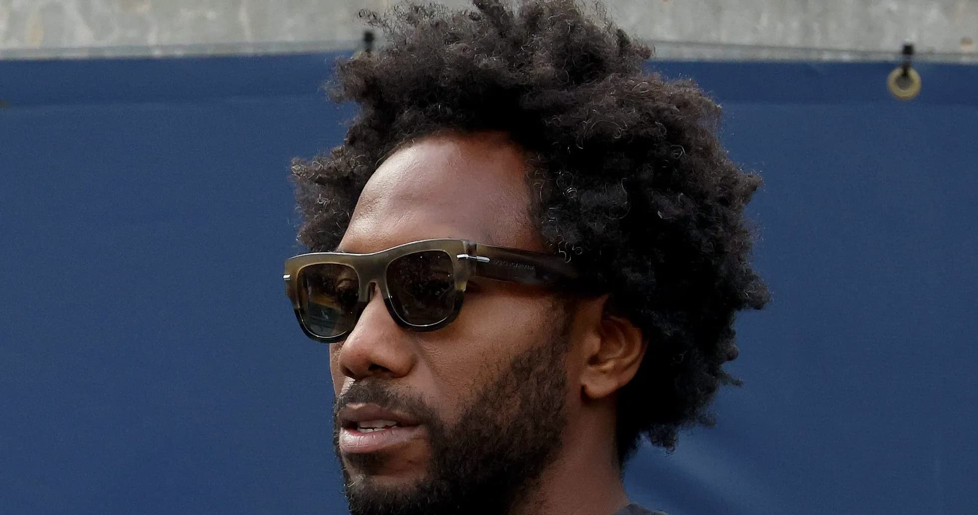 Person wearing sunglasses with curly hair outdoors