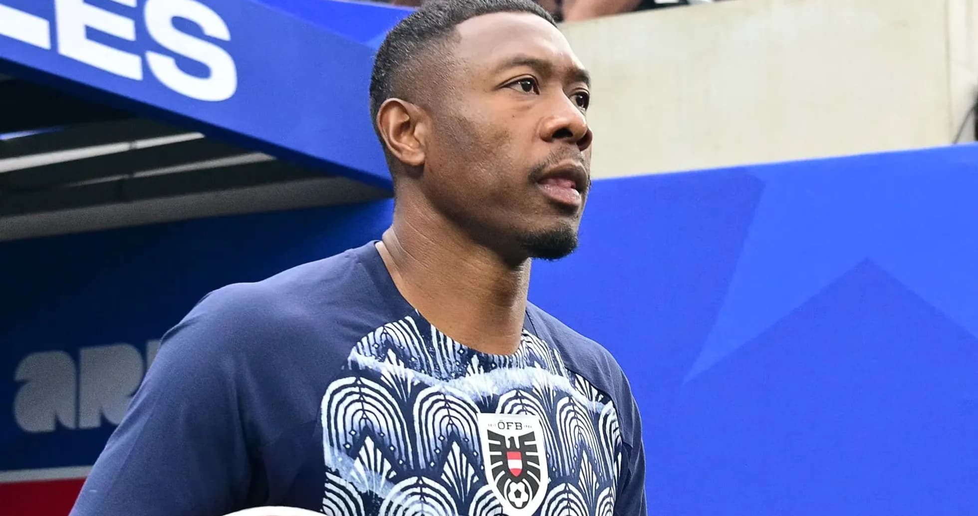 Player walking onto the pitch holding a soccer ball