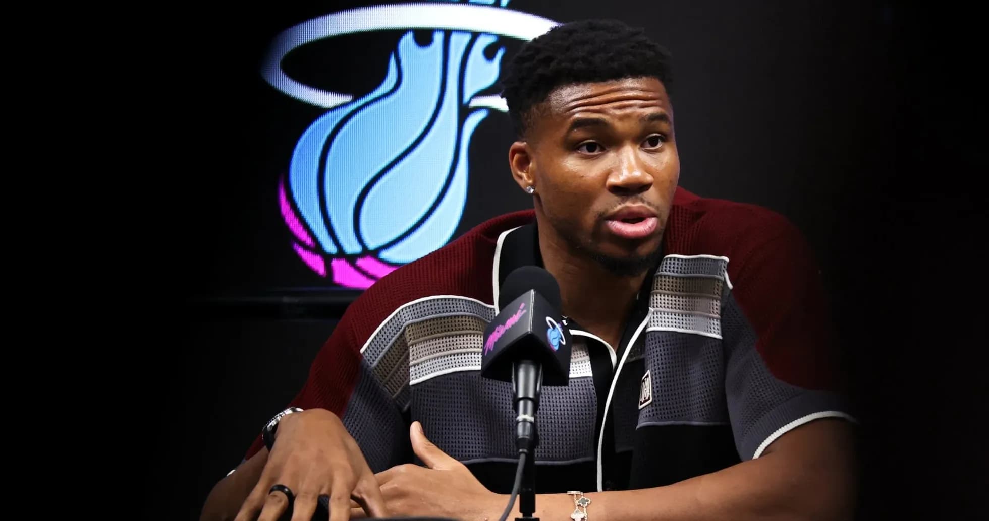 Player speaking at press conference with team logo behind