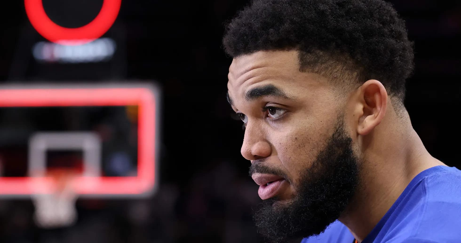 Player in blue jersey sitting near basketball hoop