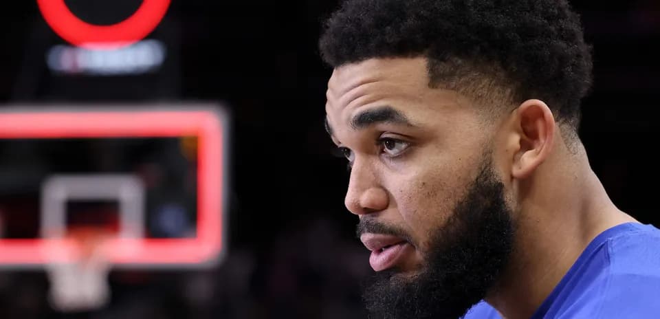 Player in blue jersey sitting near basketball hoop