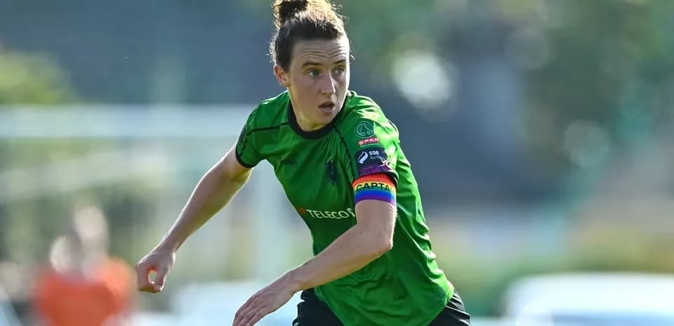 Female soccer player wearing green kit and captain's armband