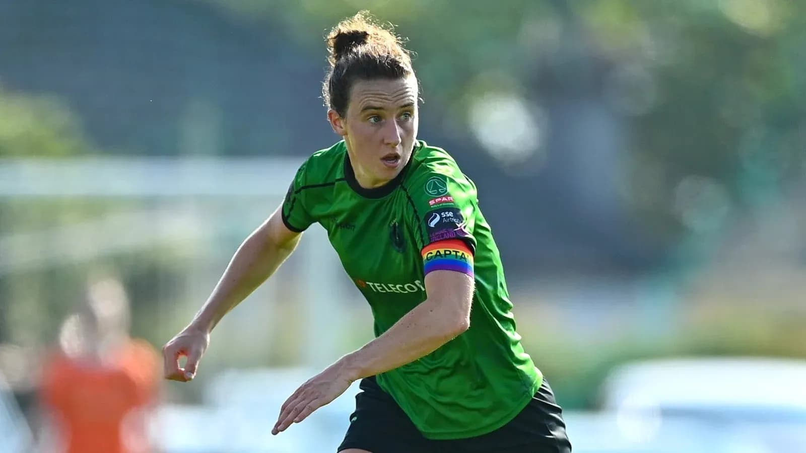 Female soccer player wearing green kit and captain's armband