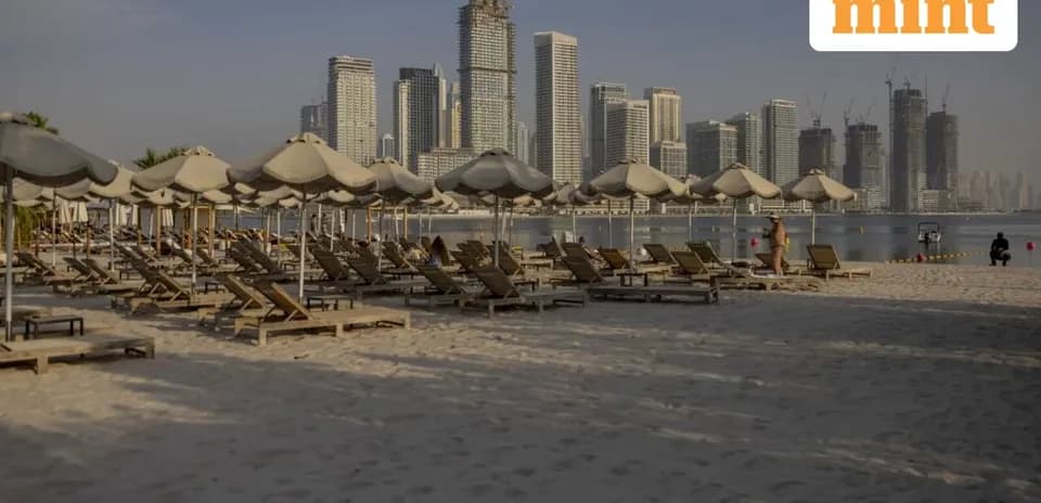 Beach loungers and umbrellas with city skyline backdrop