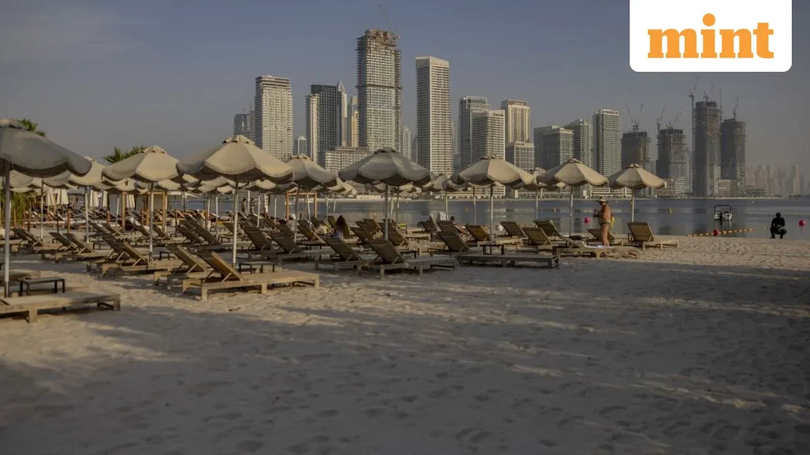 Beach loungers and umbrellas with city skyline backdrop