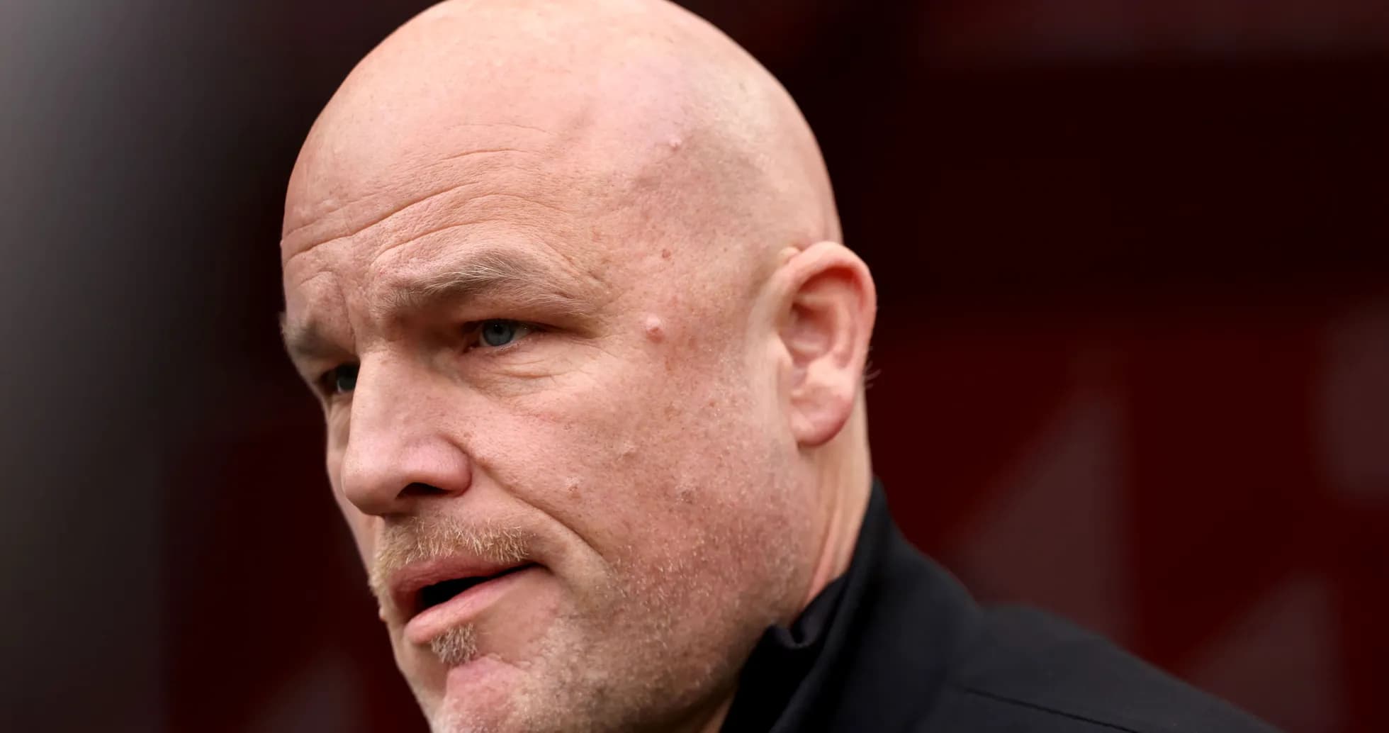 Close-up of a bald man speaking outdoors