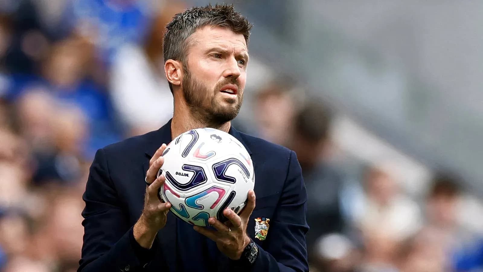 Coach holding a soccer ball on the sidelines