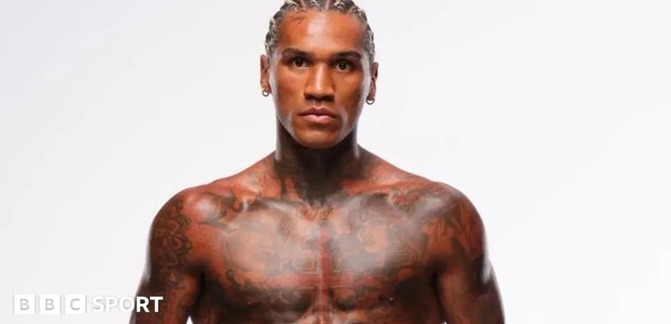 Tattooed athlete posing against plain background
