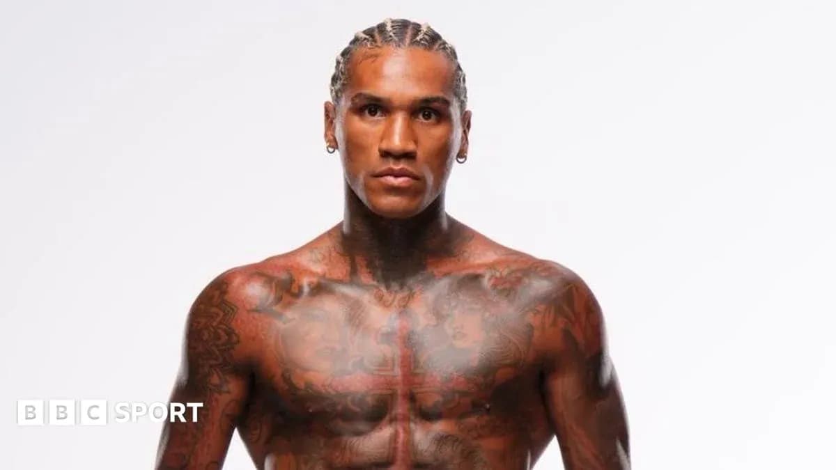 Tattooed athlete posing against plain background