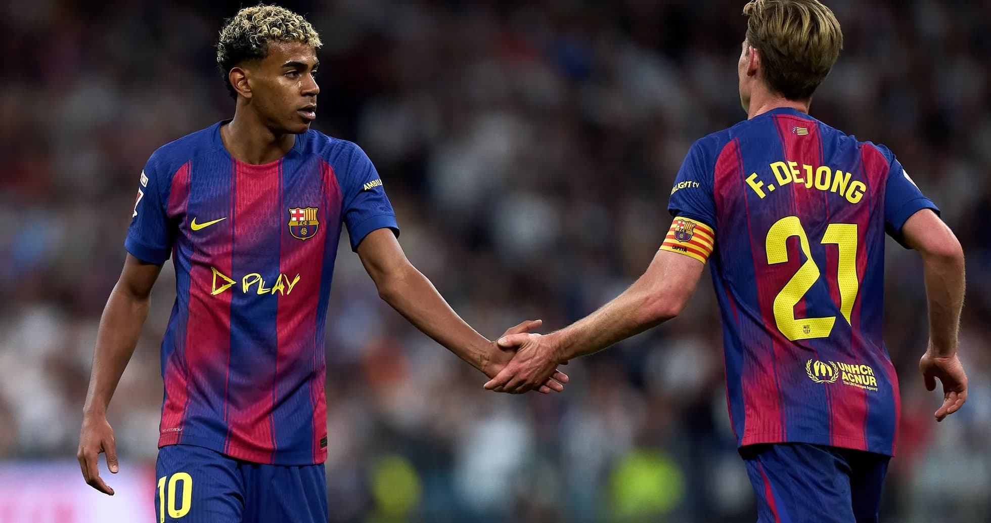 Two FC Barcelona players exchanging handshakes on field