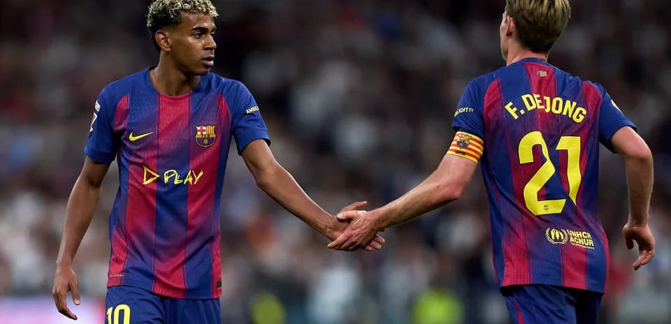 Two FC Barcelona players exchanging handshakes on field