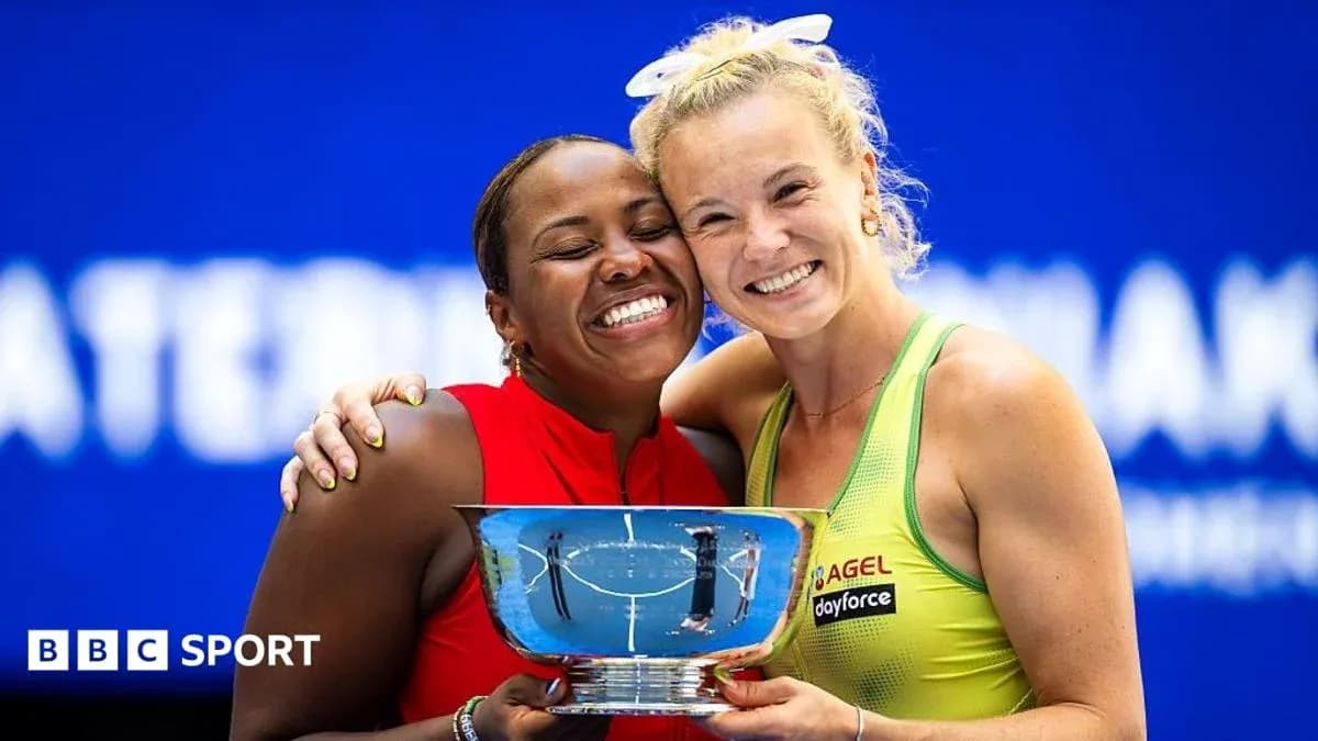 Two tennis players celebrating with trophy after match
