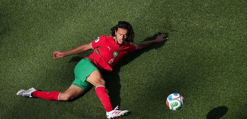 Moroccan player sliding on grass towards ball