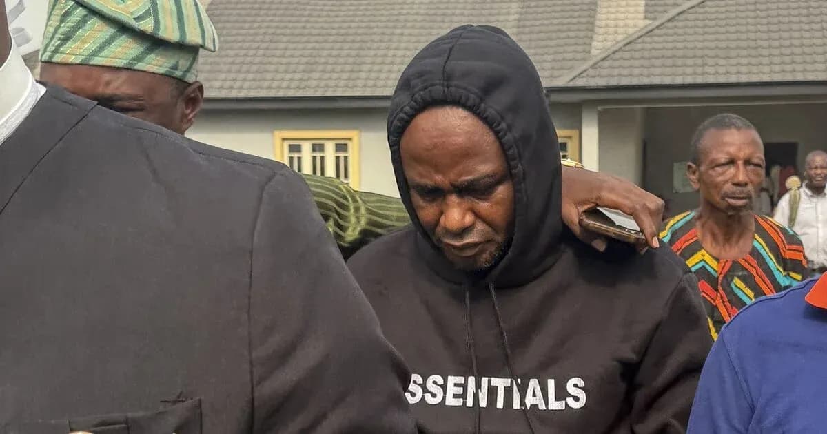 Man in hoodie being escorted by others outdoors