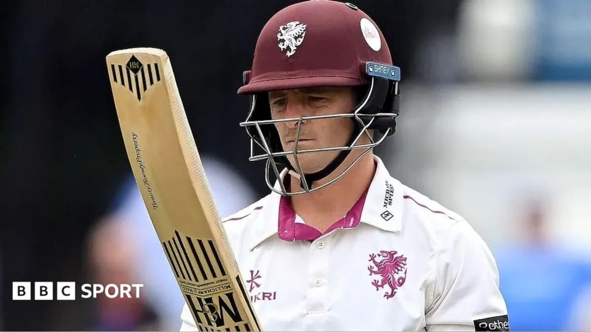Cricketer holding bat, wearing helmet and team jersey