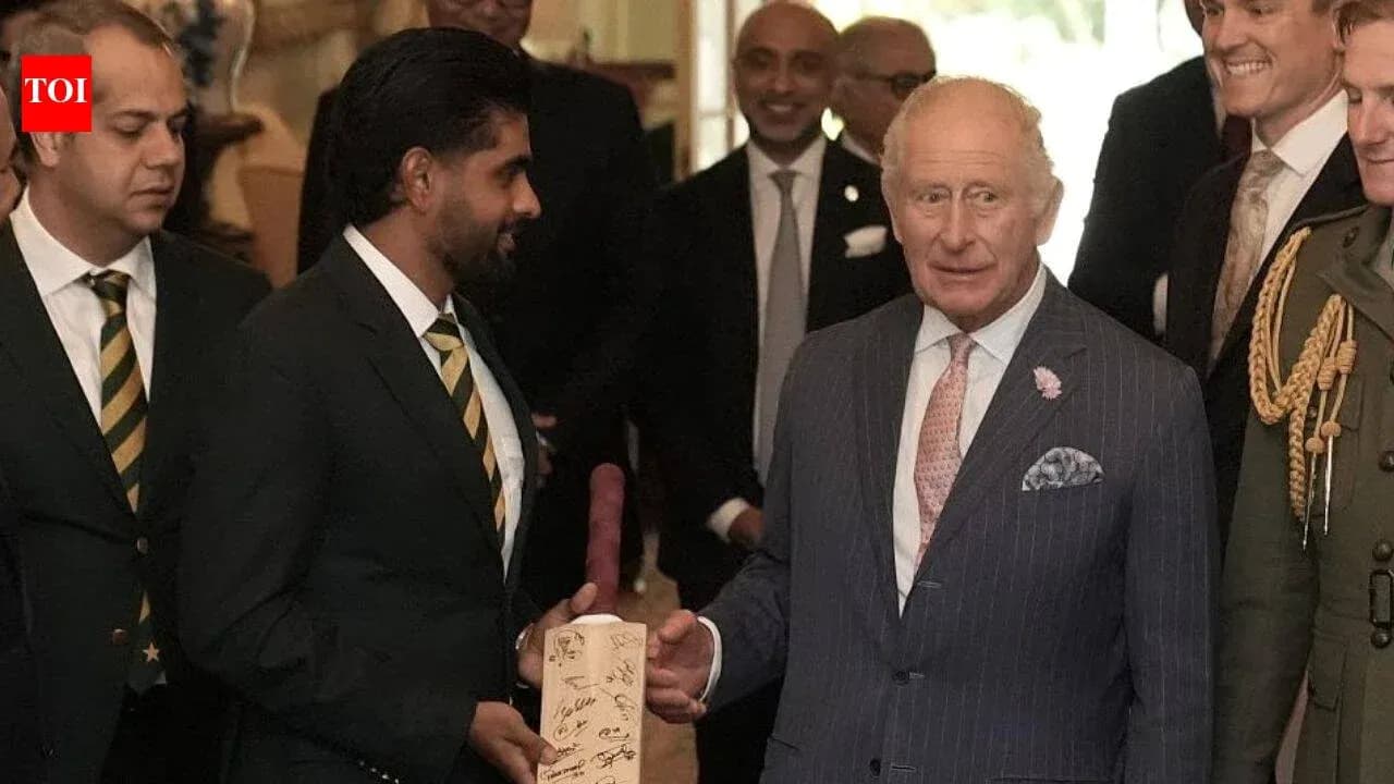 Cricket players presenting a signed bat to King Charles
