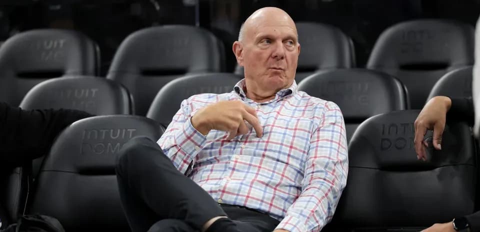 Man in checked shirt seated at basketball game