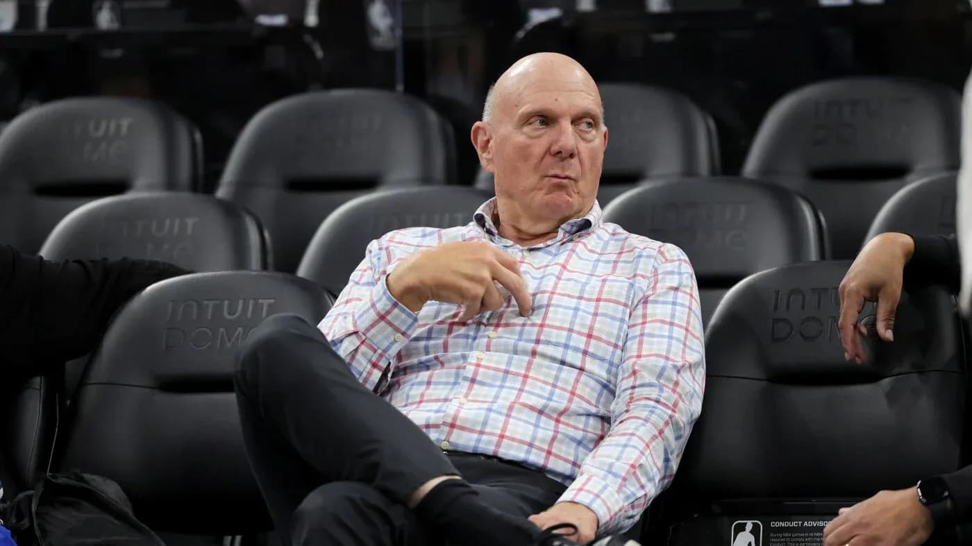 Man in checked shirt seated at basketball game