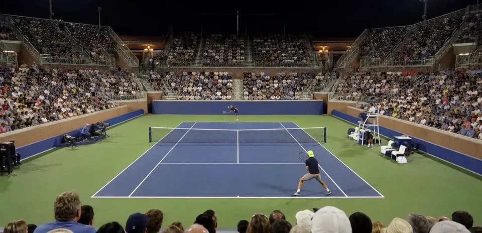 Tennis match at night with large audience present