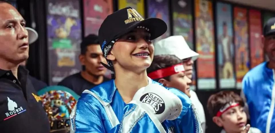 Young female boxer smiling with gloves and supporters