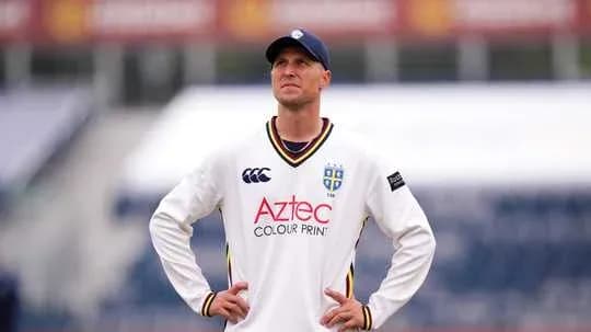 Cricketer wearing white kit looking upwards