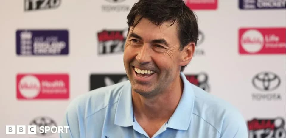 Cricket coach smiling during press conference