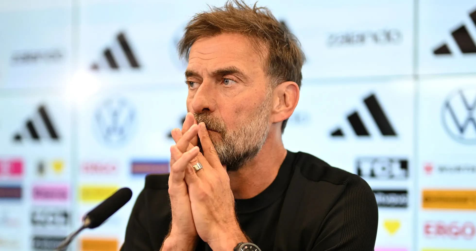 Manager at press conference with microphone and logos