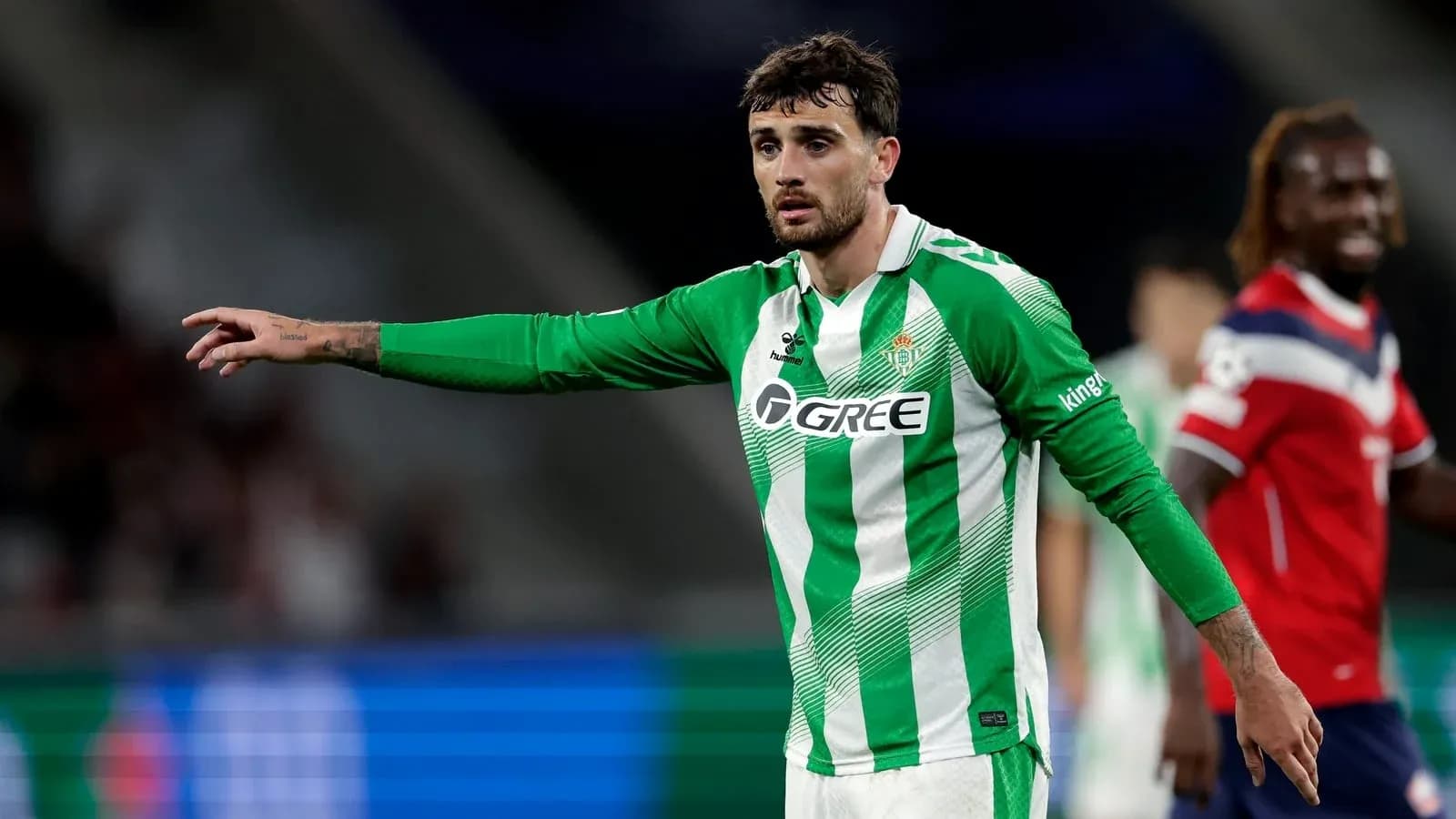 Player in green and white kit directing teammates during match