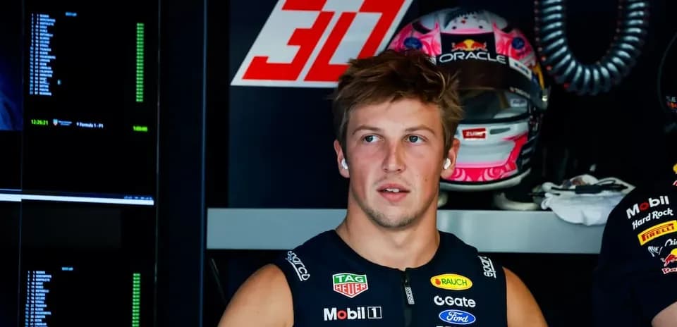 Driver in pit area with racing helmet behind