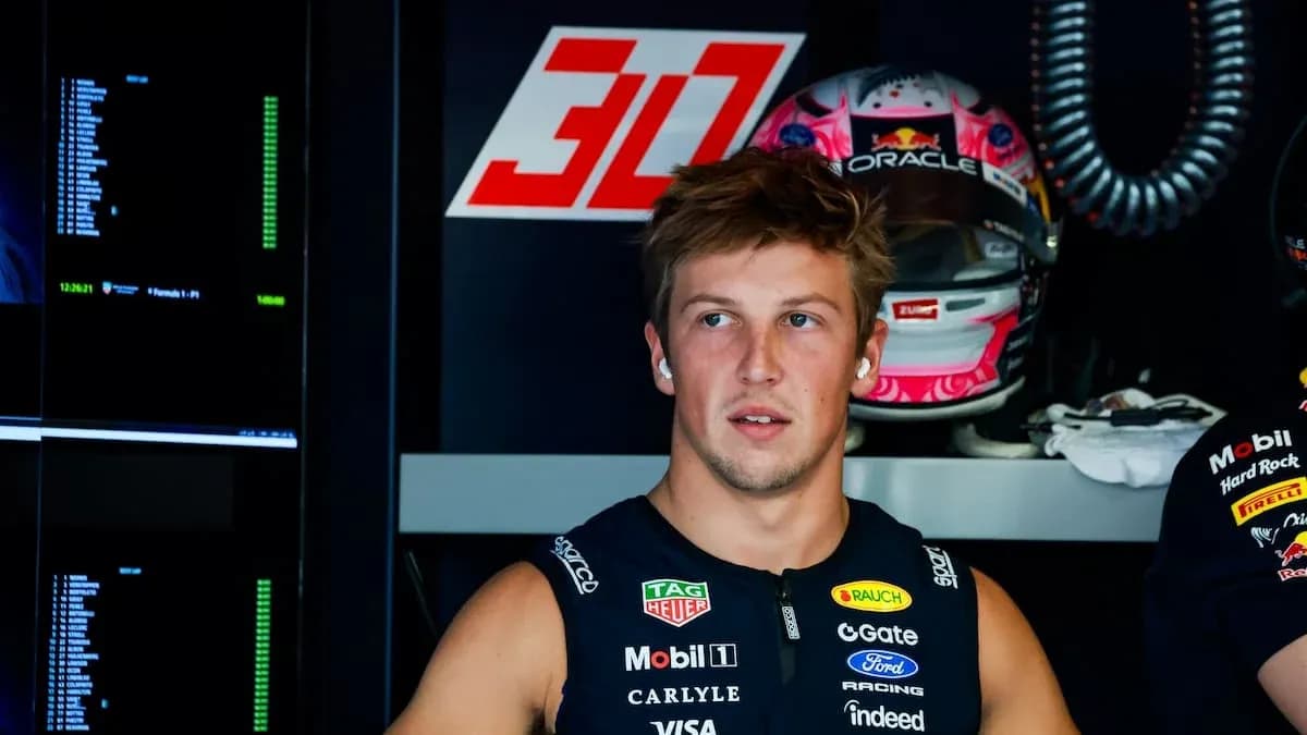 Driver in pit area with racing helmet behind