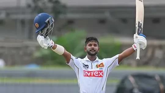 Batsman celebrating century with raised bat and helmet