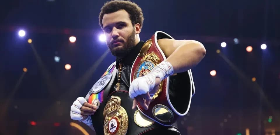 Boxer posing with championship belts in arena