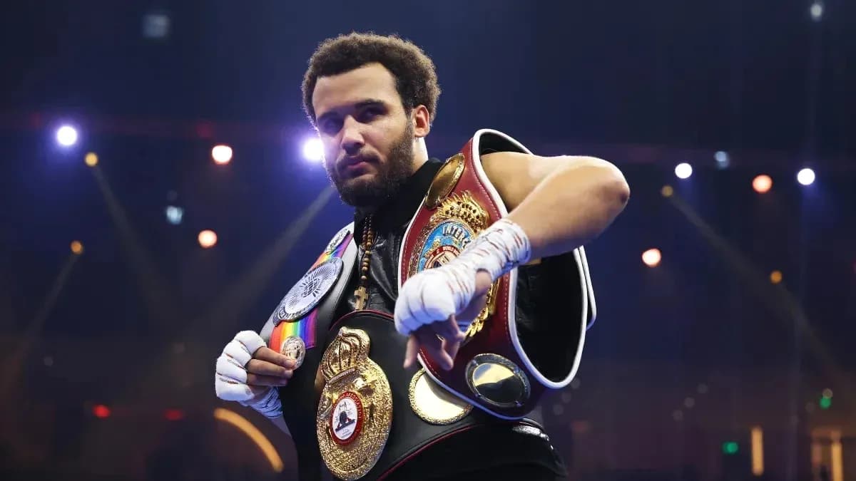 Boxer posing with championship belts in arena
