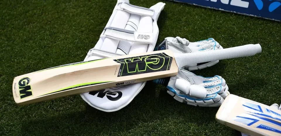 Cricket bat and gloves on the grass field