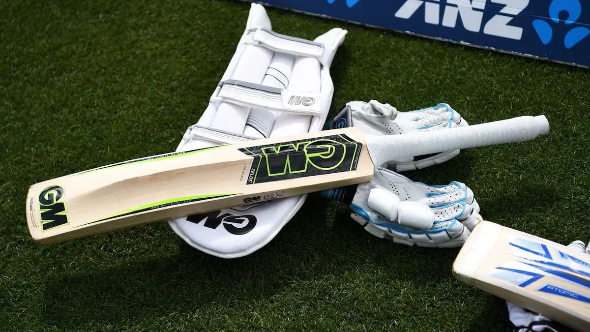 Cricket bat and gloves on the grass field