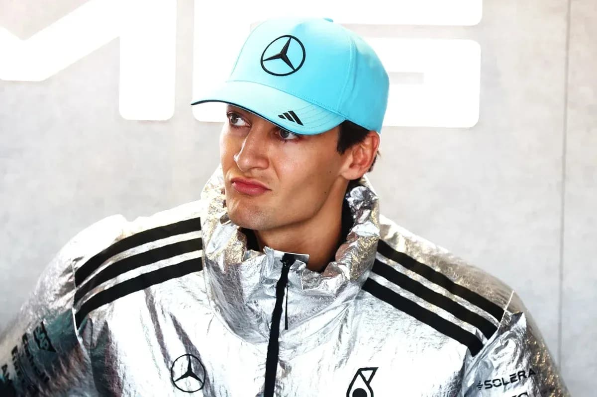 Driver wearing silver jacket and blue cap in paddock