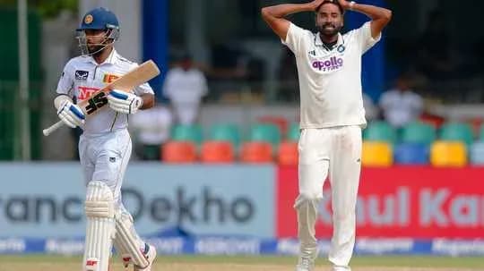 Batsman in white kit with bat; bowler in action