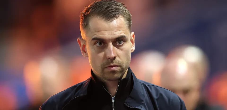 Man in jacket walking on sidelines during match