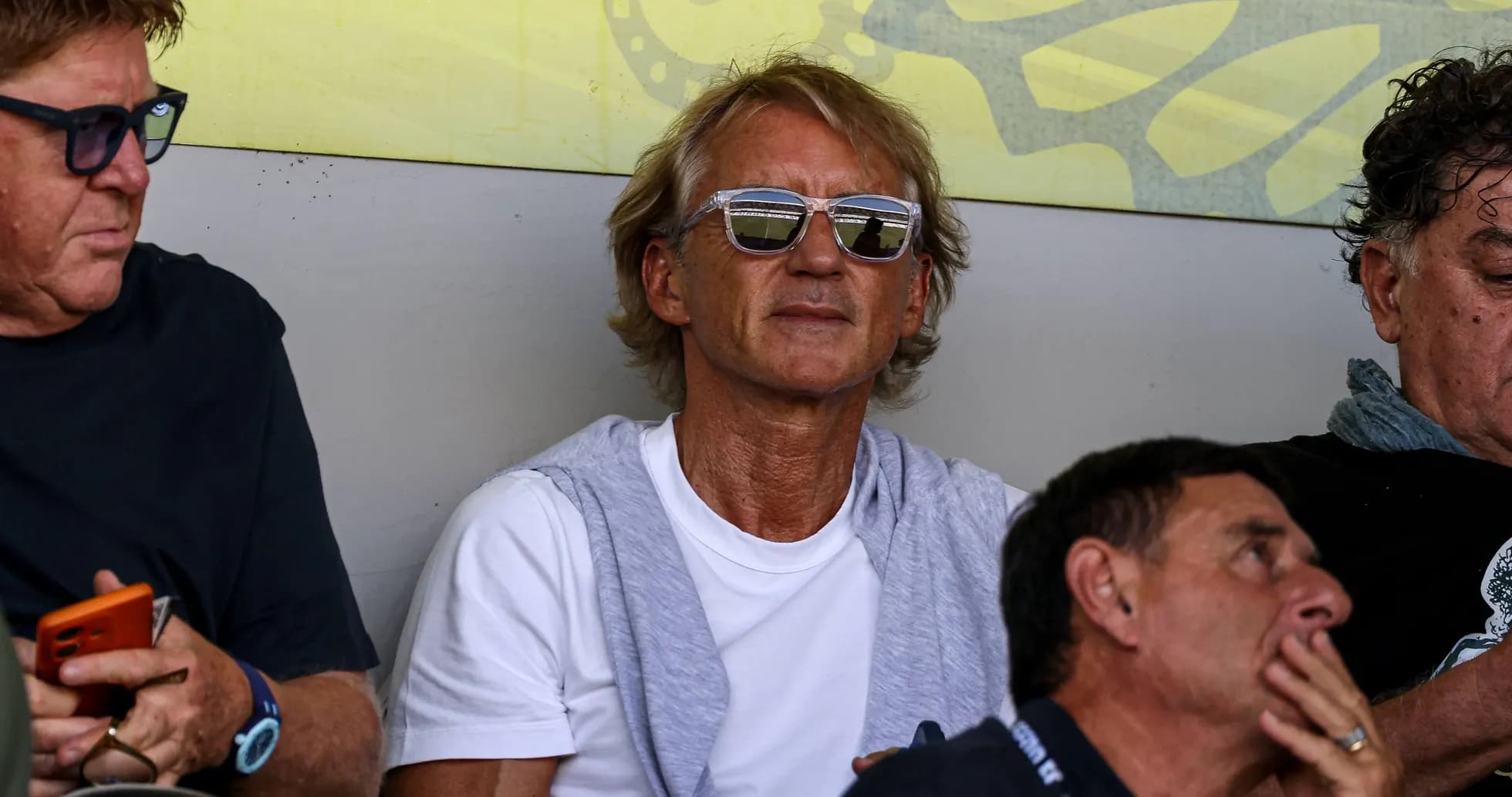 Man wearing sunglasses seated among spectators