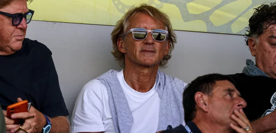 Man wearing sunglasses seated among spectators