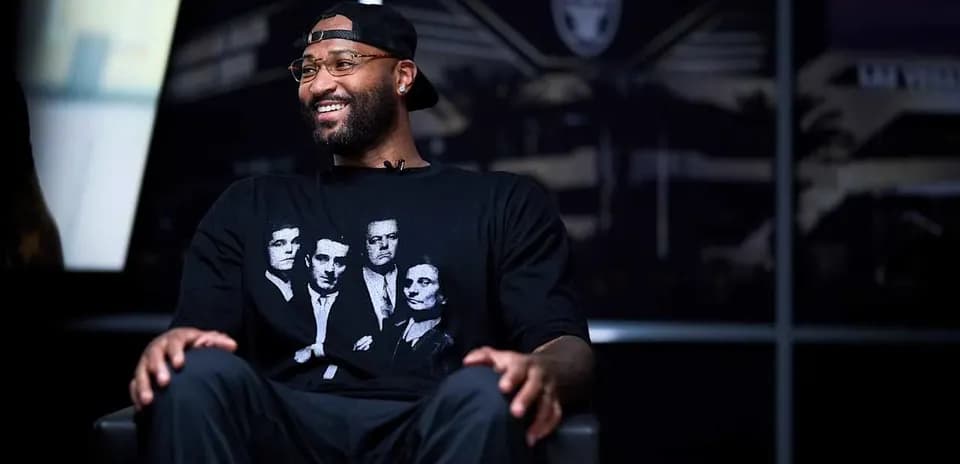 Player seated in interview with Raiders logo backdrop