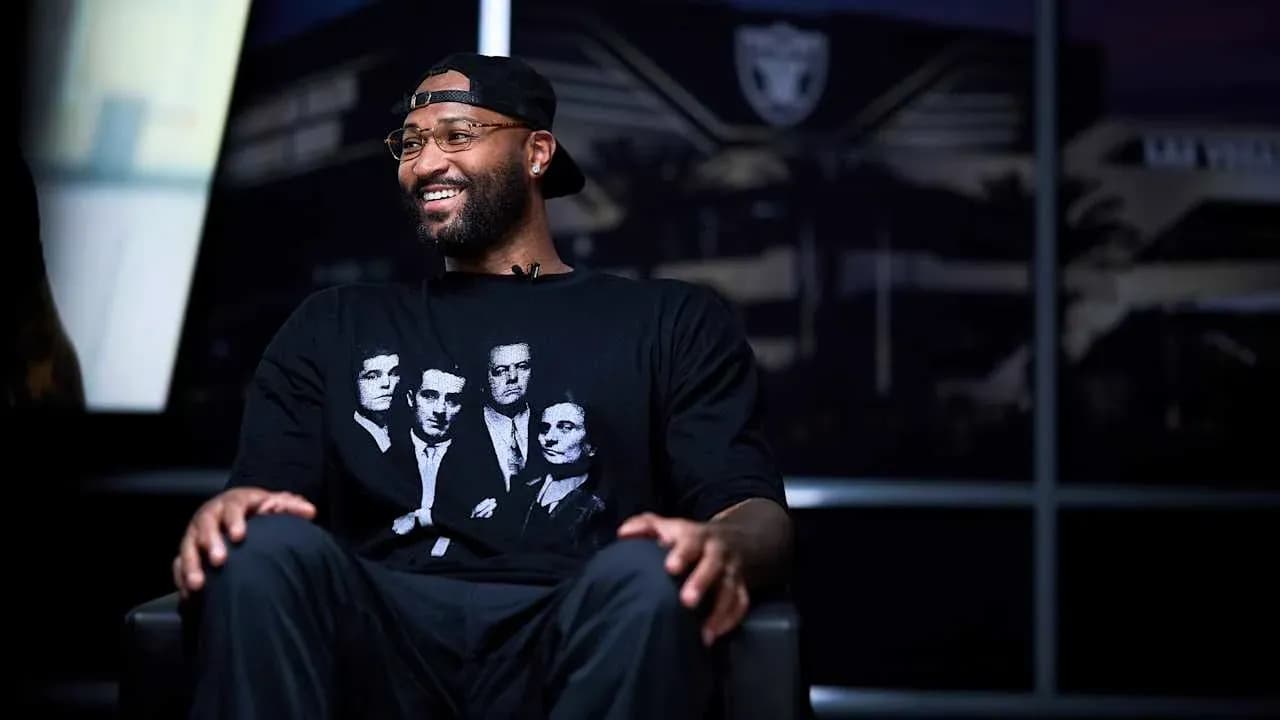 Player seated in interview with Raiders logo backdrop