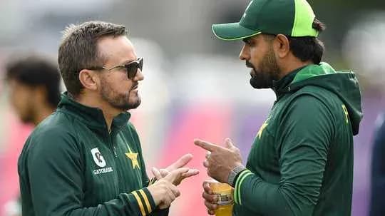 Two men in Pakistan cricket uniforms discussing strategies